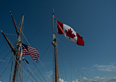 Canadian and American Flags Flying Together on Ship Mast